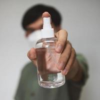 Handsome man put on a mask holding alcohol spray bottle cleaner photo