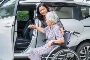 Help and support asian senior or elderly old lady woman patient sitting on wheelchair prepare get to her car, healthy strong medical concept. photo