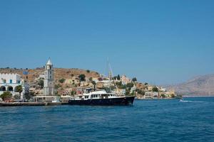 vista de la colorida isla Symi con un gran barco negro. symi, grecia foto