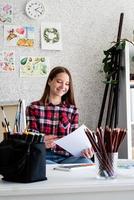 Hermosa mujer artista en camisa a cuadros pintando un cuadro en casa foto