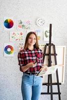 Hermosa mujer artista en camisa a cuadros pintando un cuadro en casa foto