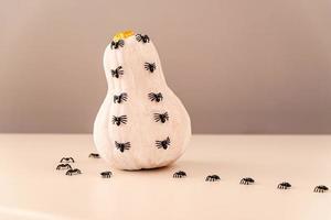 White and gold halloween spooky pumpkin with spiders crawling on white table