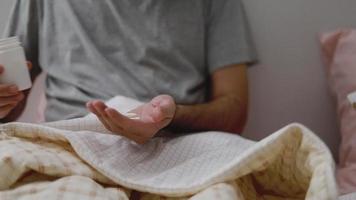 uomo asiatico che prende le pillole nel palmo della sua mano mentre è in camera da letto a casa. video