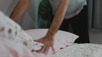le couvre-lit tactile pour homme asiatique arrange les coussins après le réveil dans la chambre. video