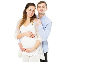 Feliz pareja amorosa esperando el nacimiento del niño posando sobre un fondo blanco. foto