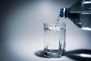 pouring water into a glass from a plastic bottle photo