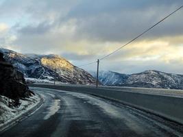 conduciendo al amanecer por el fiordo sobre hielo negro, noruega.