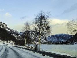 Driving at sunrise by the fjord on black ice, Norway. photo