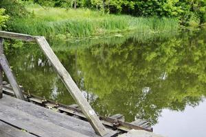 Beautifully standing old wooden bridge over river in colored background photo