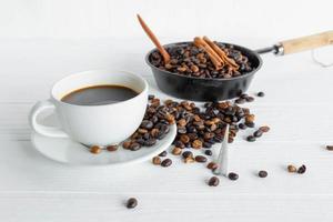 Taza de café y granos de café en la mesa de madera blanca