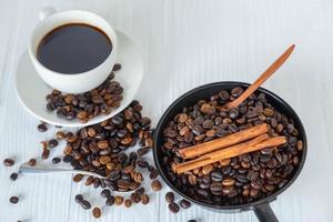 Taza de café y granos de café en la mesa de madera blanca