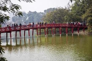 hanoi, vietnam, 2 de marzo de 2017 - personas no identificadas en huc bridge en hanoi, vietnam. este puente rojo de madera conecta la isla de jade con la orilla del lago hoan kiem. foto