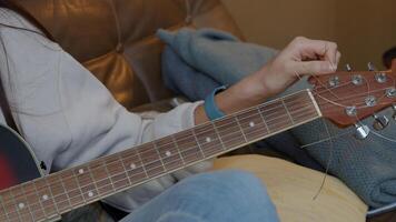 Hand with mobile phone of young Middle Eastern man holding in front of guitar of young mixed race woman, turning tuner of guitar photo