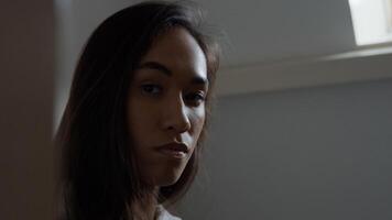 Close up, profile of young mixed race woman, looking straight ahead, turns face to camera, eyes blinking photo