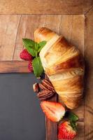 Black chalkboard with croissant and berries photo