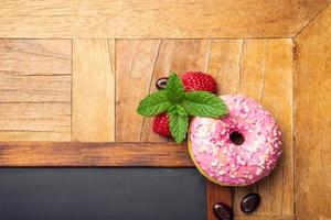 pizarra negra con rosquilla glaseada rosa foto