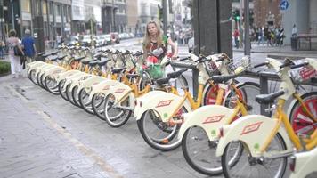 Mujer toma bicicleta de transporte público en el centro de Milán video