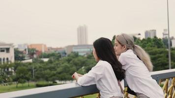 Asian lesbian couples enjoy traveling and talking while standing on the bridge.