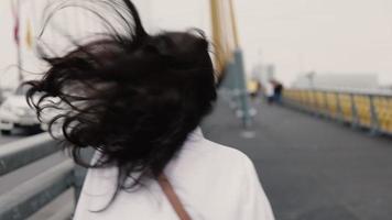 Aziatische vrouw die op de brug loopt. video