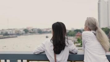 casais de lésbicas asiáticos desfrutando de viajar e conversar em pé na ponte.
