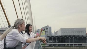 asiatische lesbische Paare, die Seifenblasen spielen, während sie auf der Brücke stehen. video