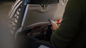 homem asiático usando um smartphone no avião. video