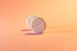 Two pills in an orange-pink background. Medical theme.