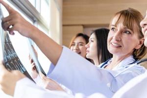 Senior doctor woman teaching doctor student woman. How to analyze the X-ray film. Radiology department photo