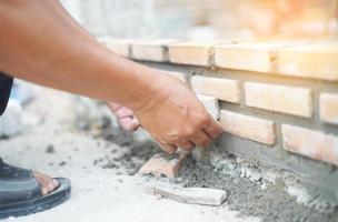 Close up of industrial bricklayer installing bricks on construction site photo