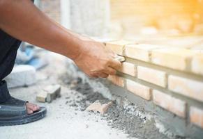 Cerca de albañil industrial instalando ladrillos en sitio en construcción foto