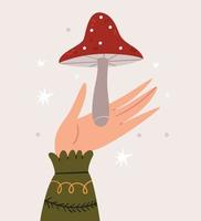 una mano en un suéter caliente sostiene una amanita. linda ilustración de otoño. vector