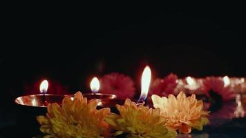 felice "Diwali. bruciando lampade a olio diya e fiori su sfondo scuro. tradizionale celebrazione della festa della luce. video