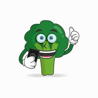 Personaje de mascota de brócoli sosteniendo un teléfono celular. ilustración vectorial vector