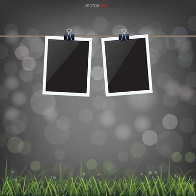 Blank photo frame in green grass field and light blurred bokeh background. Vector.