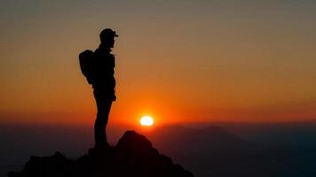 montañista en la cima de la montaña viendo la fantástica puesta de sol foto