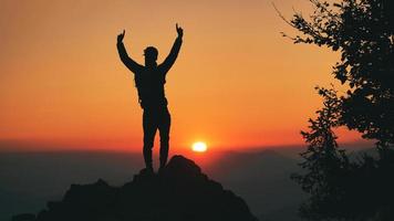 Man in silhouette in front of idyllic sunset in the hills photo