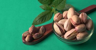 Pistachios or Pista nuts decorated with green leaves. plain background, top view.Flat lay. photo