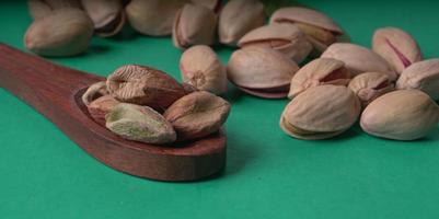 Pistachios or Pista nuts decorated with green leaves. plain background, top view.Flat lay. photo