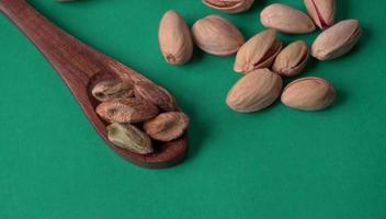 Pistachios or Pista nuts decorated with green leaves. plain background, top view.Flat lay. photo