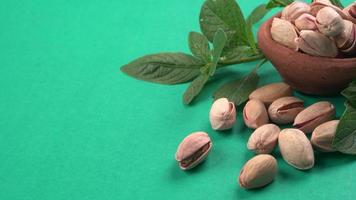 Pistachios or Pista nuts decorated with green leaves. plain background, top view.Flat lay. photo