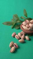 Pistachios or Pista nuts decorated with green leaves. plain background, top view.Flat lay. photo