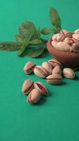 Pistachios or Pista nuts decorated with green leaves. plain background, top view.Flat lay. photo