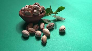 Pistachios or Pista nuts decorated with green leaves. plain background, top view.Flat lay. photo