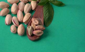 Pistachios or Pista nuts decorated with green leaves. plain background, top view.Flat lay. photo