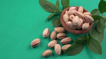 Pistachios or Pista nuts decorated with green leaves. plain background, top view.Flat lay. photo