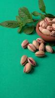 Pistachios or Pista nuts decorated with green leaves. plain background, top view.Flat lay. photo