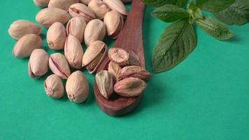 Pistachios or Pista nuts decorated with green leaves. plain background, top view.Flat lay. photo