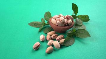 Pistachios or Pista nuts decorated with green leaves. plain background, top view.Flat lay.