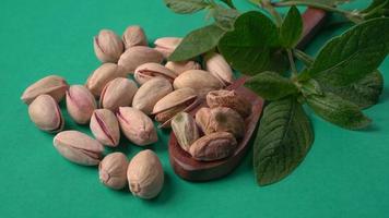 Pistachios or Pista nuts decorated with green leaves. plain background, top view.Flat lay. photo