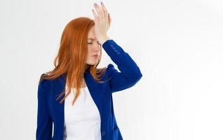 Cute, young beautiful red hair woman do facepalm. Redhead girl headache failed to upset business face palm. Portrait of female doing facepalm posing against studio background. photo